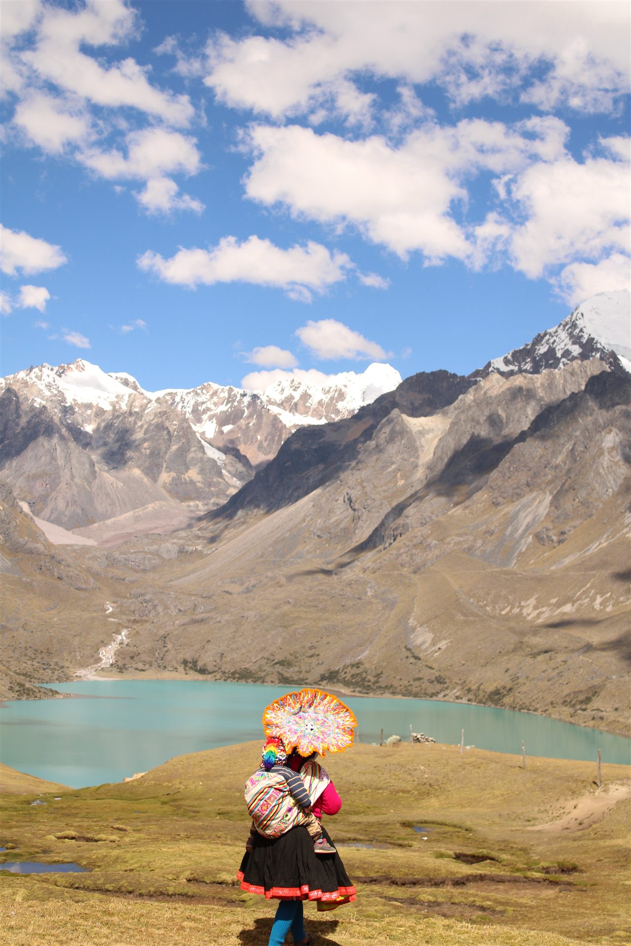 Traditional Peruvian dress beside a turquoise mountain lake