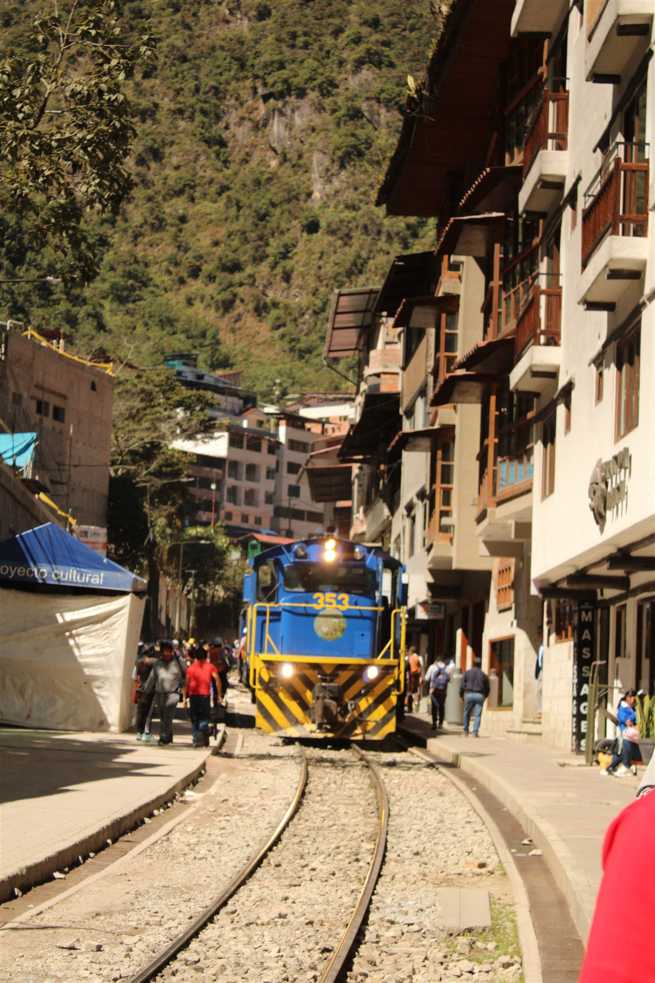 Blue train traveling through a town near Machu Picchu