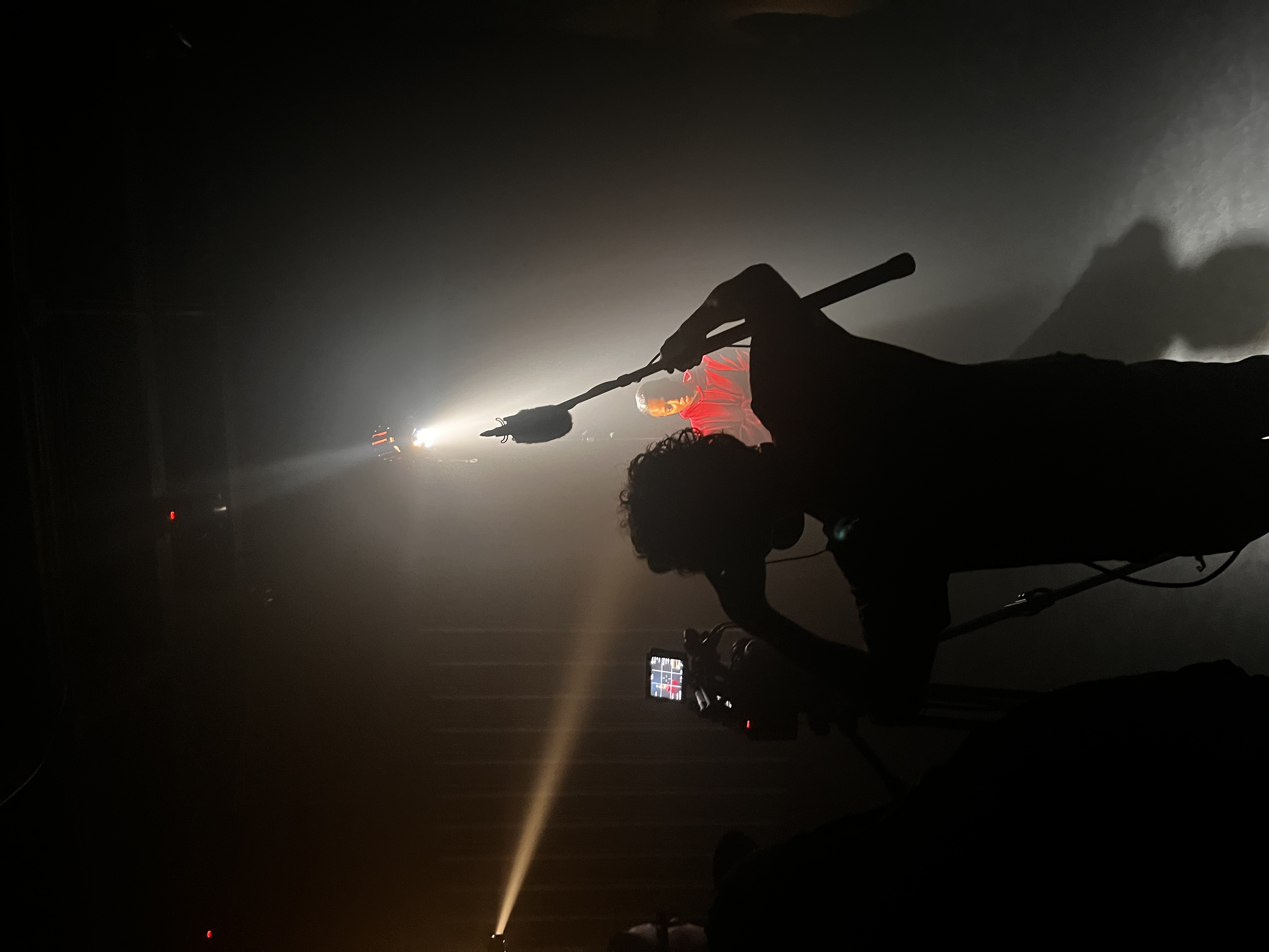 Production crew filming a performer under dramatic lighting